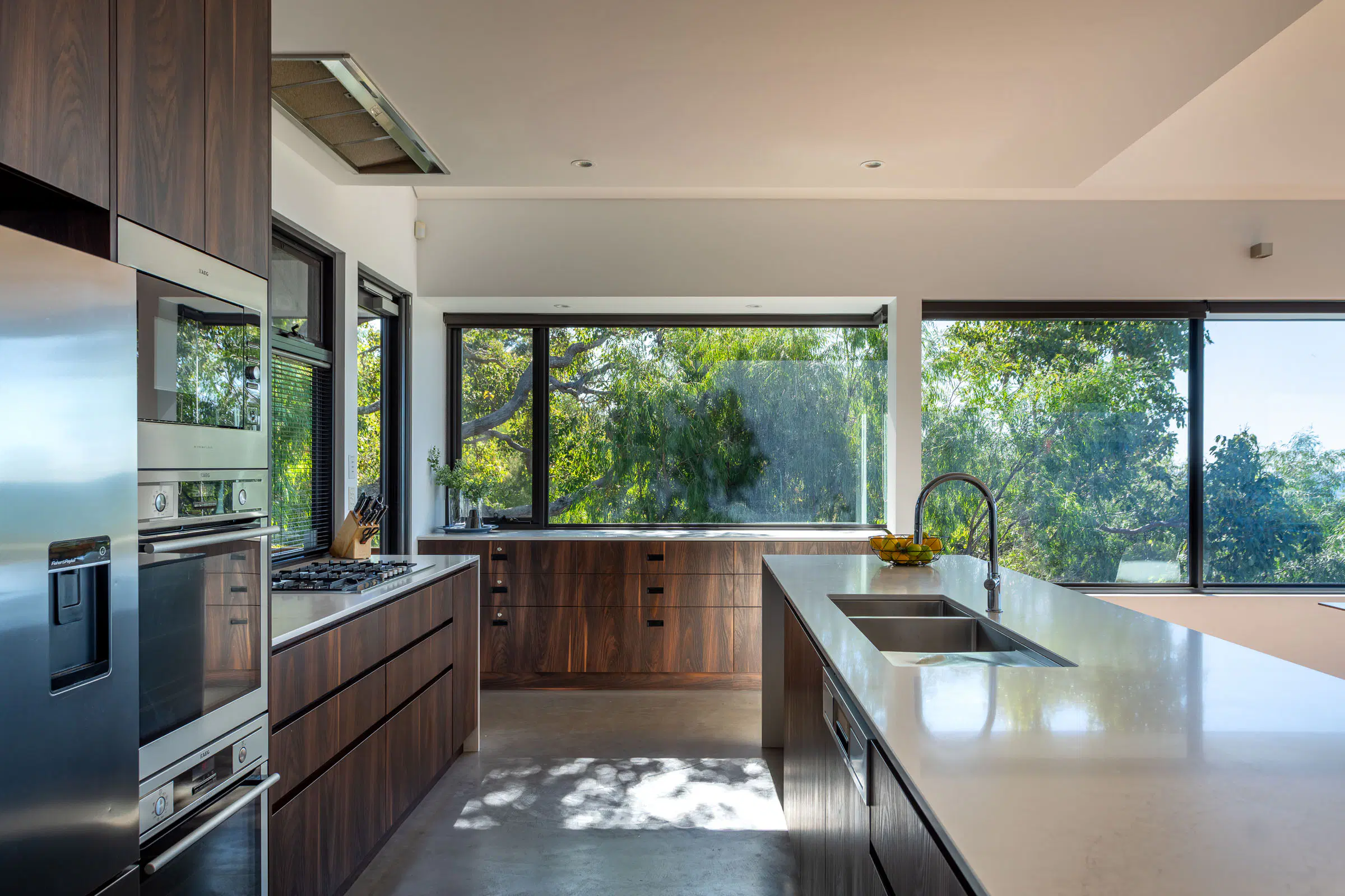 Kitchen detail — timber joinery, stone bench, a window to the trees