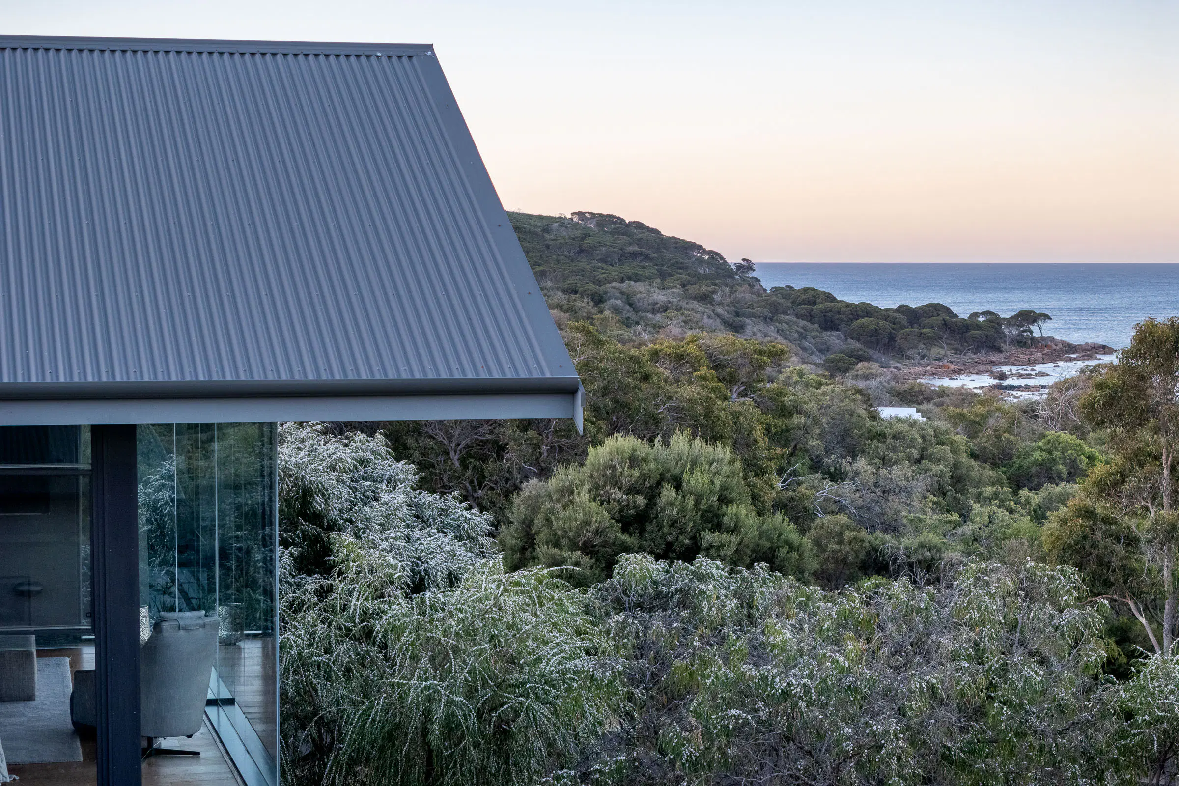 The roofline at dusk, looking over the bush to the ocean